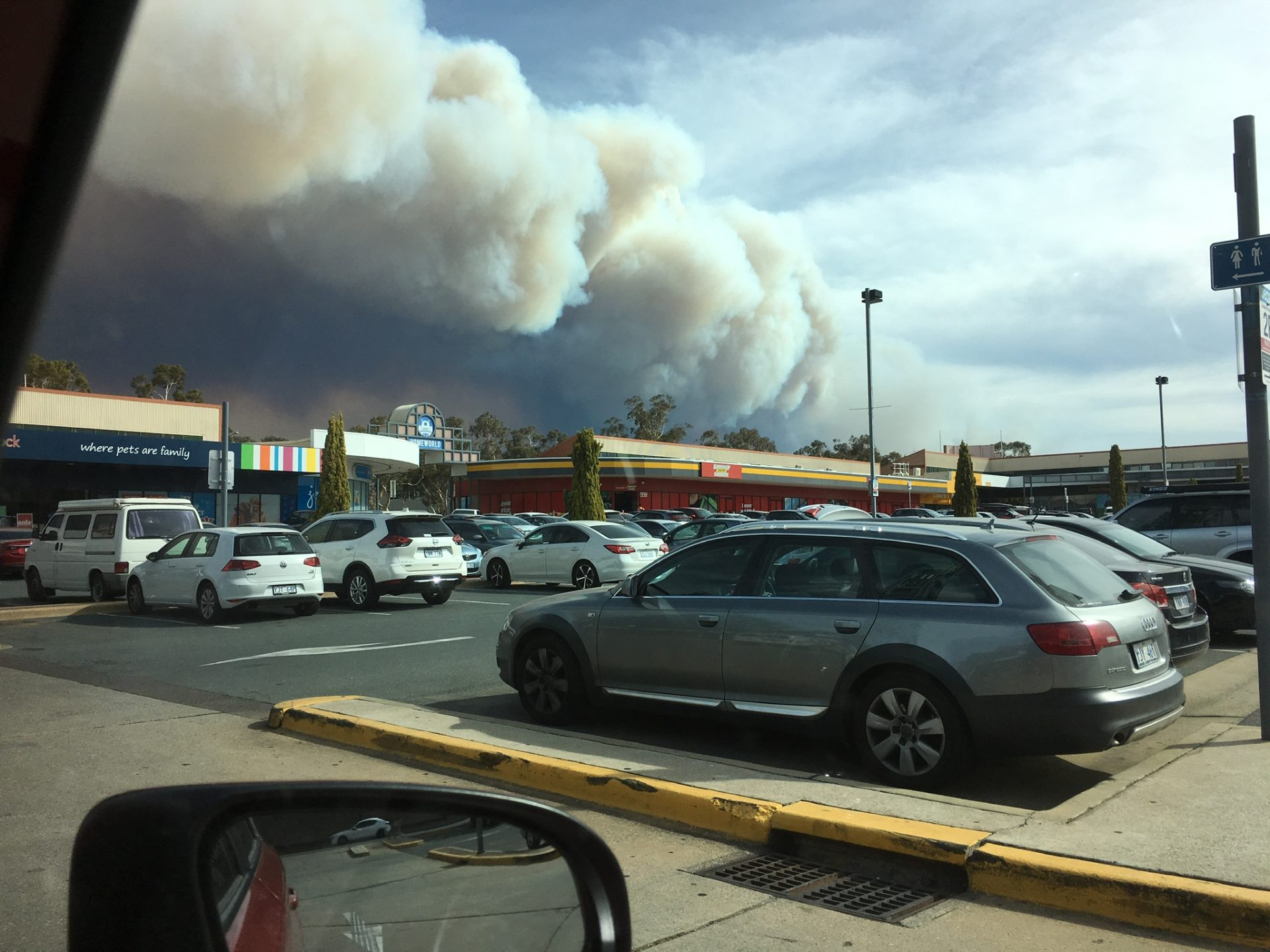 Smoke billowing over shopping centre in a car park