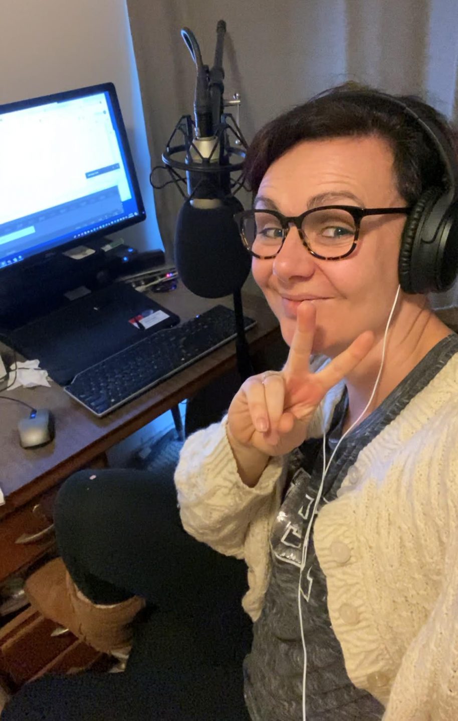 Tegan Taylor smiling showing a peace sign in front of a computer and microphone