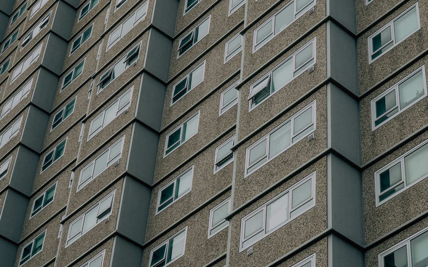 Detailed view of the side of an apartment block, with some windows open, some closed.