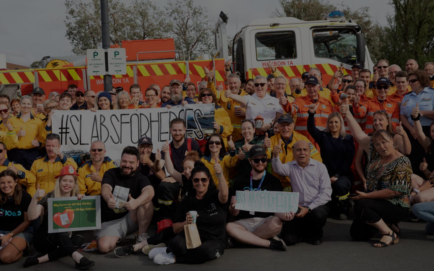 A large group of people, mainly dressed in volunteer firefighting uniforms, in front of a Wamboin rural fire truck.