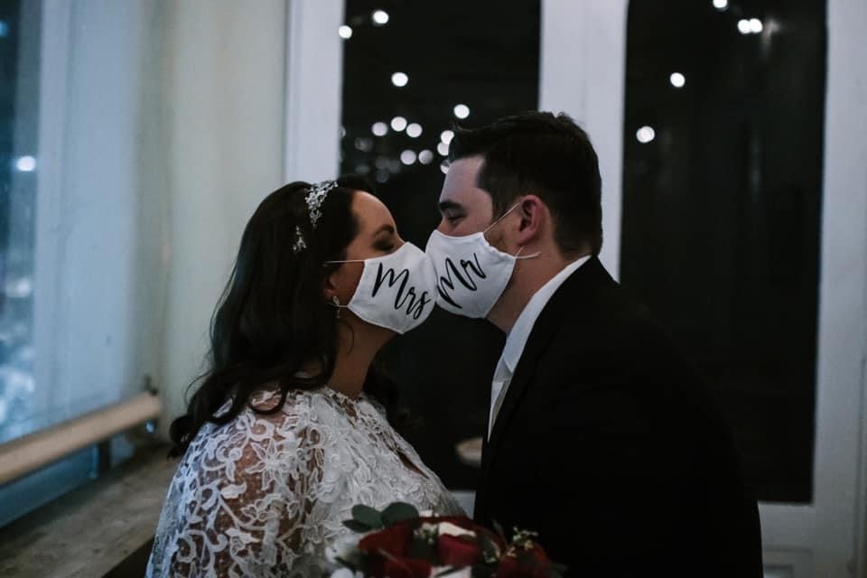 Man and woman kissing with masks on.