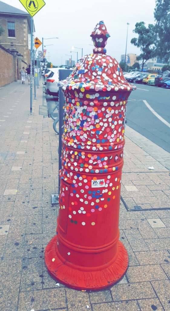 Red post box covered in round coloured stickers