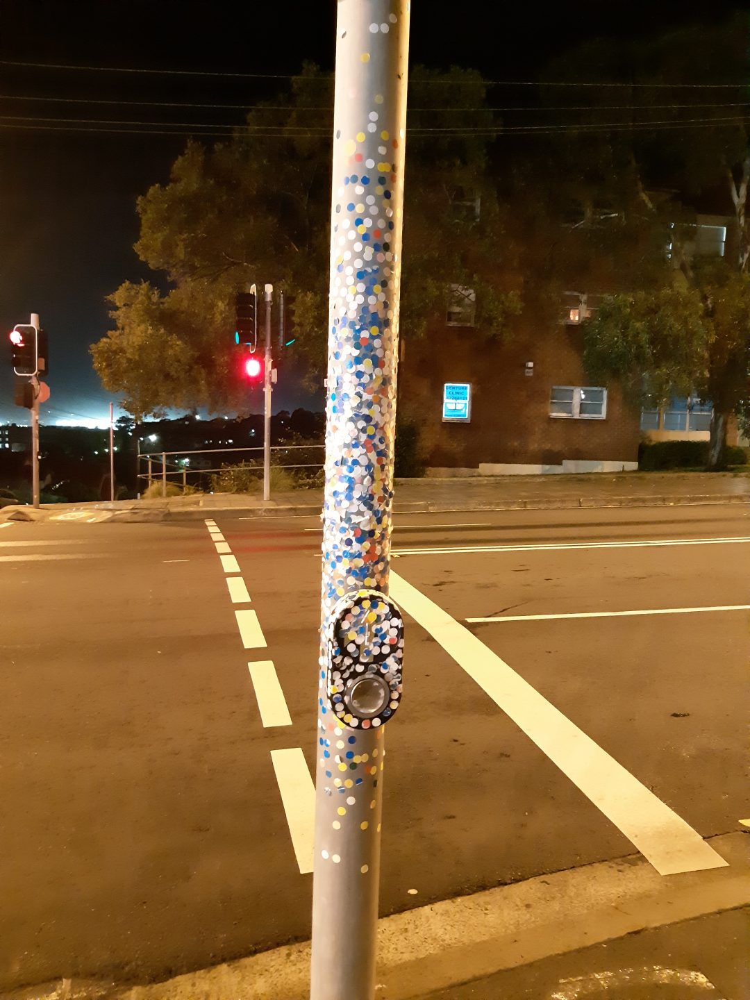 Traffic light pedestrian crossing button and pole covered in coloured stickers