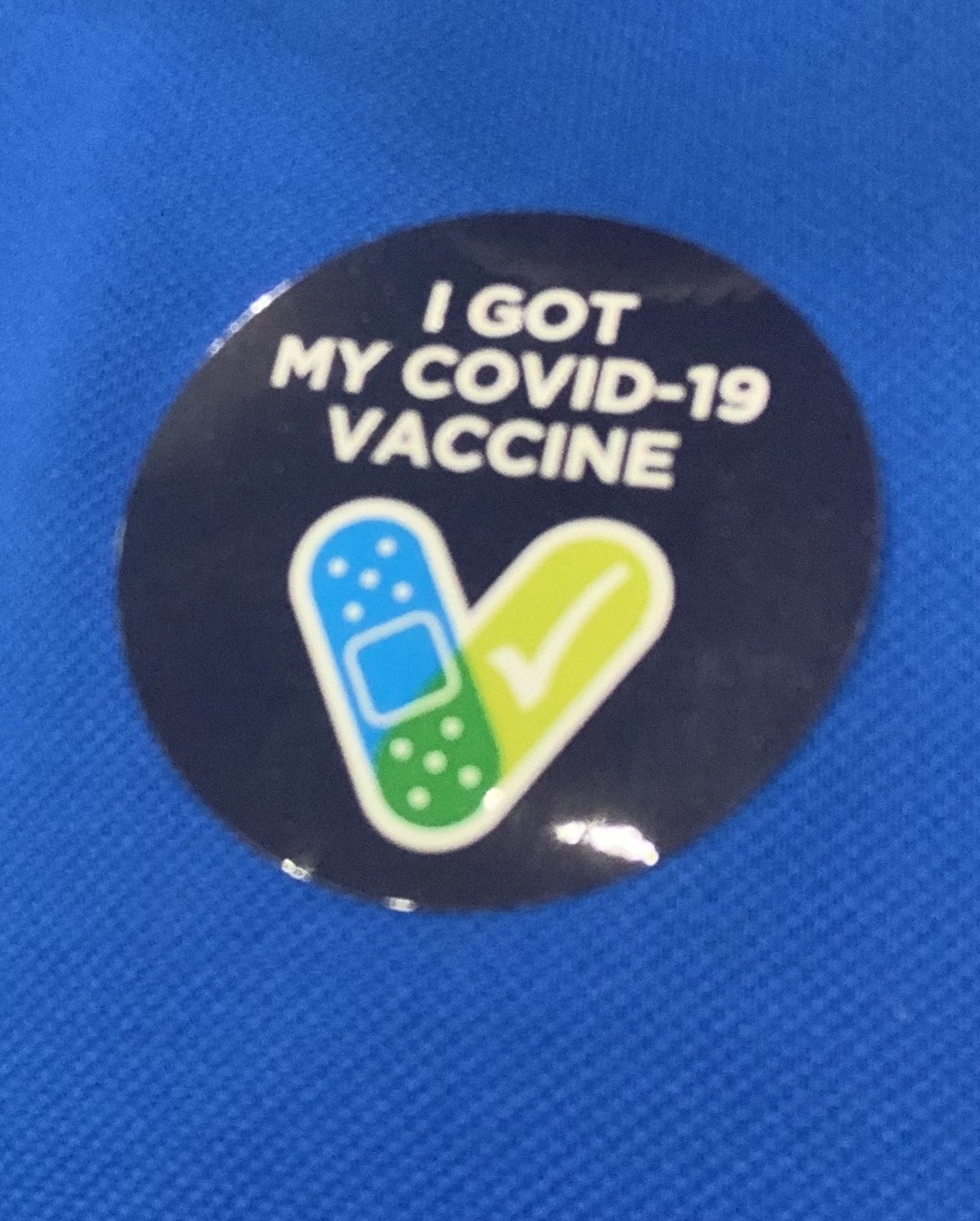 a navy sticker with white lettering, I GOT MY COVID-19 VACCINE, with a bandaid and a white tick on a green background forming a V
