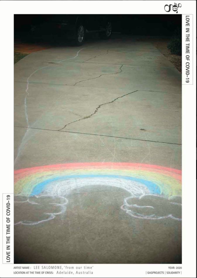 A colourful chalk drawing of a rainbow decorates a concrete pavement, while at the far edges of the work are the wheels of a shadowy car in darkness.