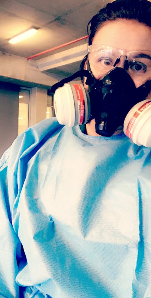 a photo of a paramedic wearing a blue protective suit, a face mask and transparent goggles.