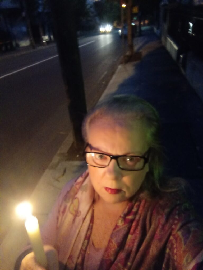 A woman holding a candle outside at dawn.