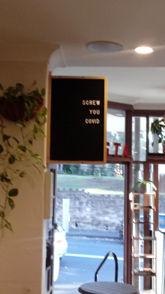 A sign in a cafe that says 'screw you covid'