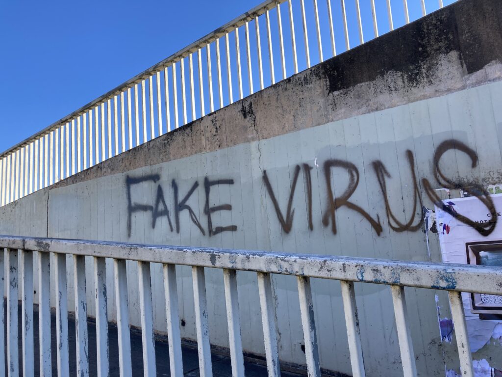 graffiti on the side of a bridge that says 'fake virus'