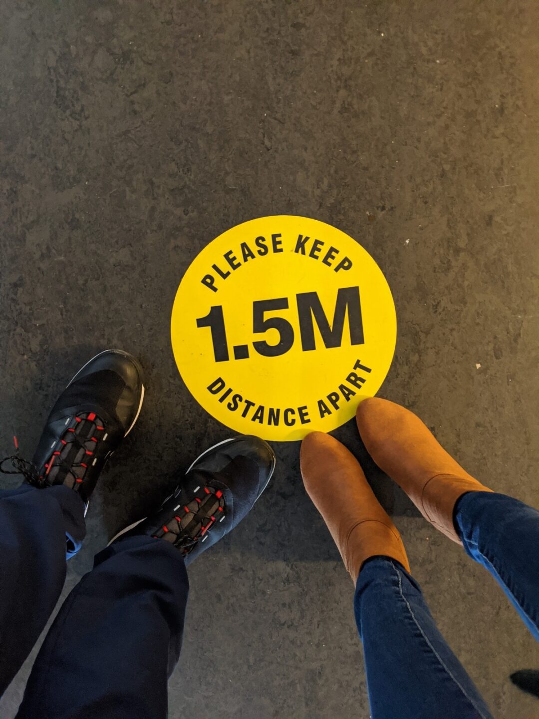 A yellow sticker on the ground telling people to keep 1.5 metres apart.