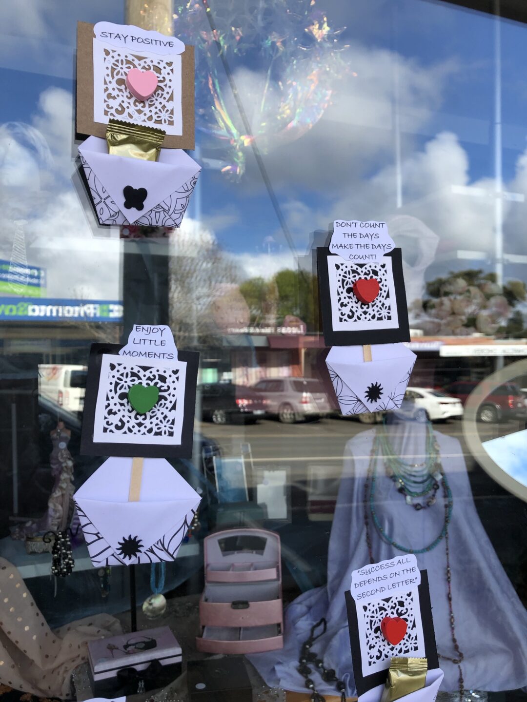 hand made pockets hanging from a shop window with sayings on them and free lollipops in them