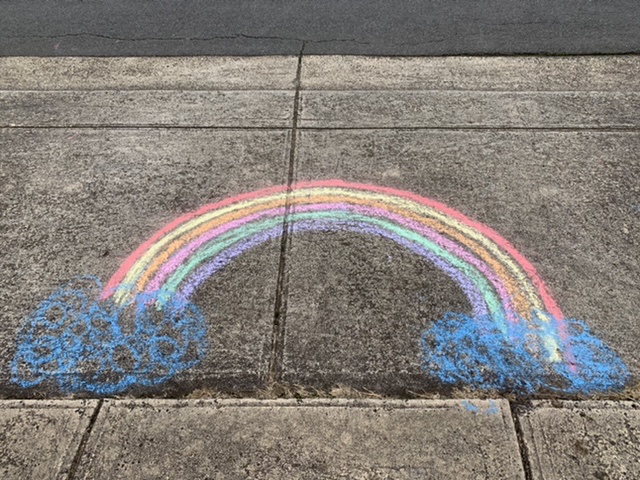 A chalk rainbow drawn on pavement.