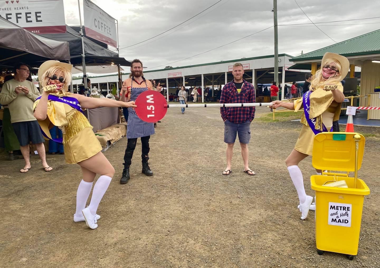 two women dressed in gold glitter outfits holding lollipop signs that say '1.5 m'