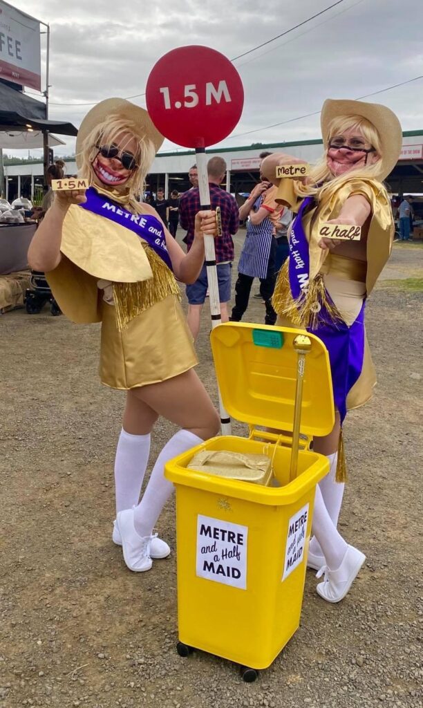 two women dressed in gold glitter outfits holding lollipop signs that say '1.5 m'