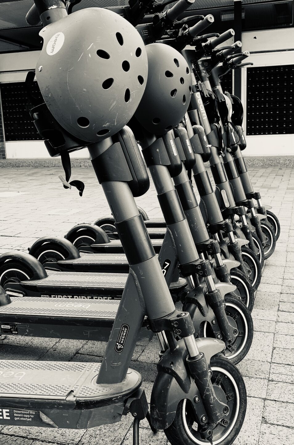 A black and white photos of e-scooters lined up.