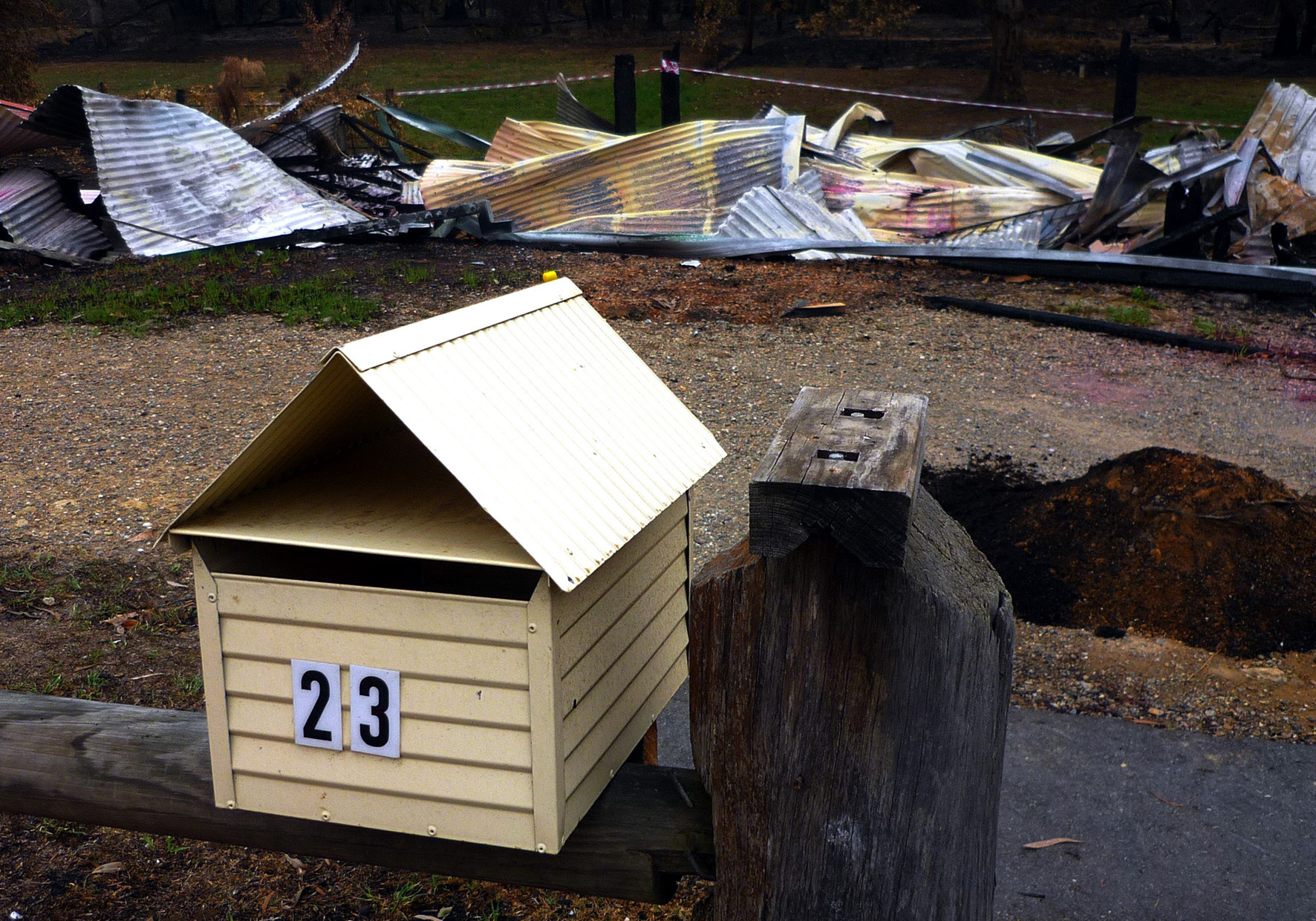 A pile of rubble behind a cream coloured letter box.