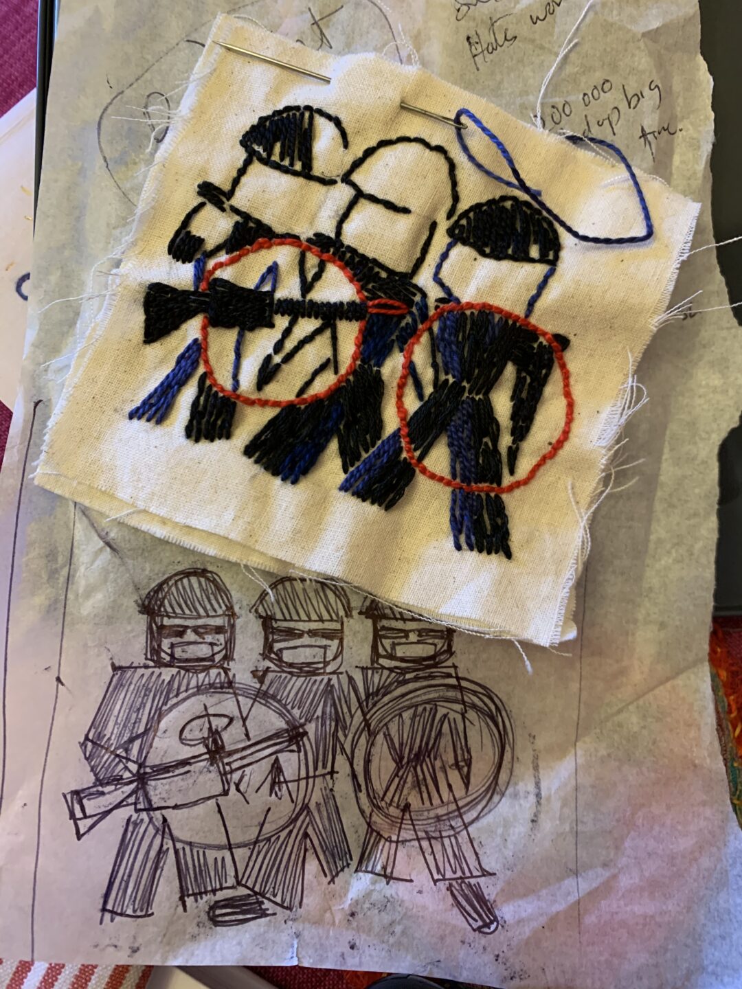 A hand stitched square and accompanying drawing o three figures probably police