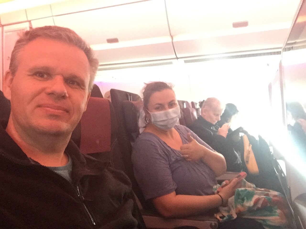 a couple on a plane and one wearing a mask.