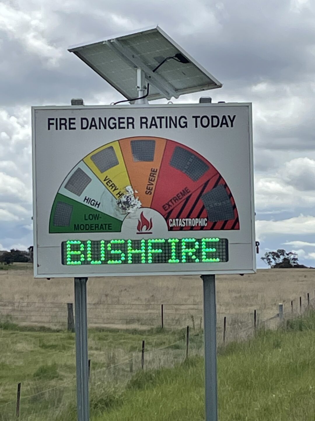 A bush fire safety rating sign that says 'BUSHFIRE' in green lights as the rating.
