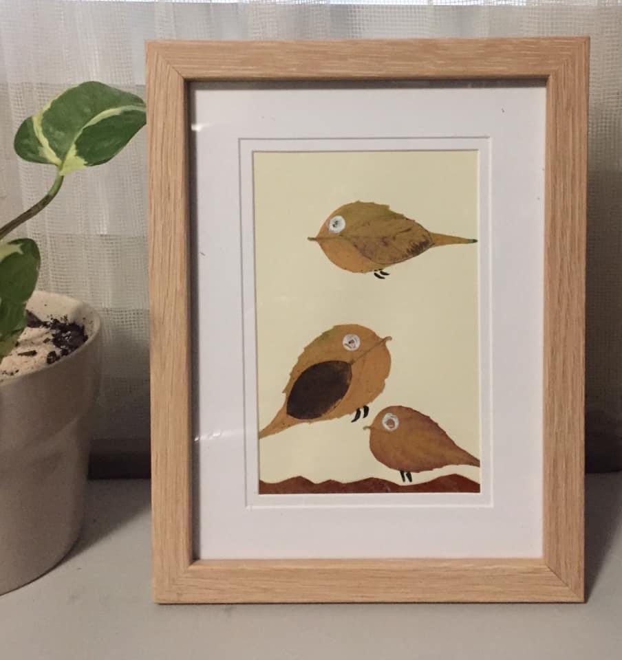 an artwork made of leaves featuring three birds