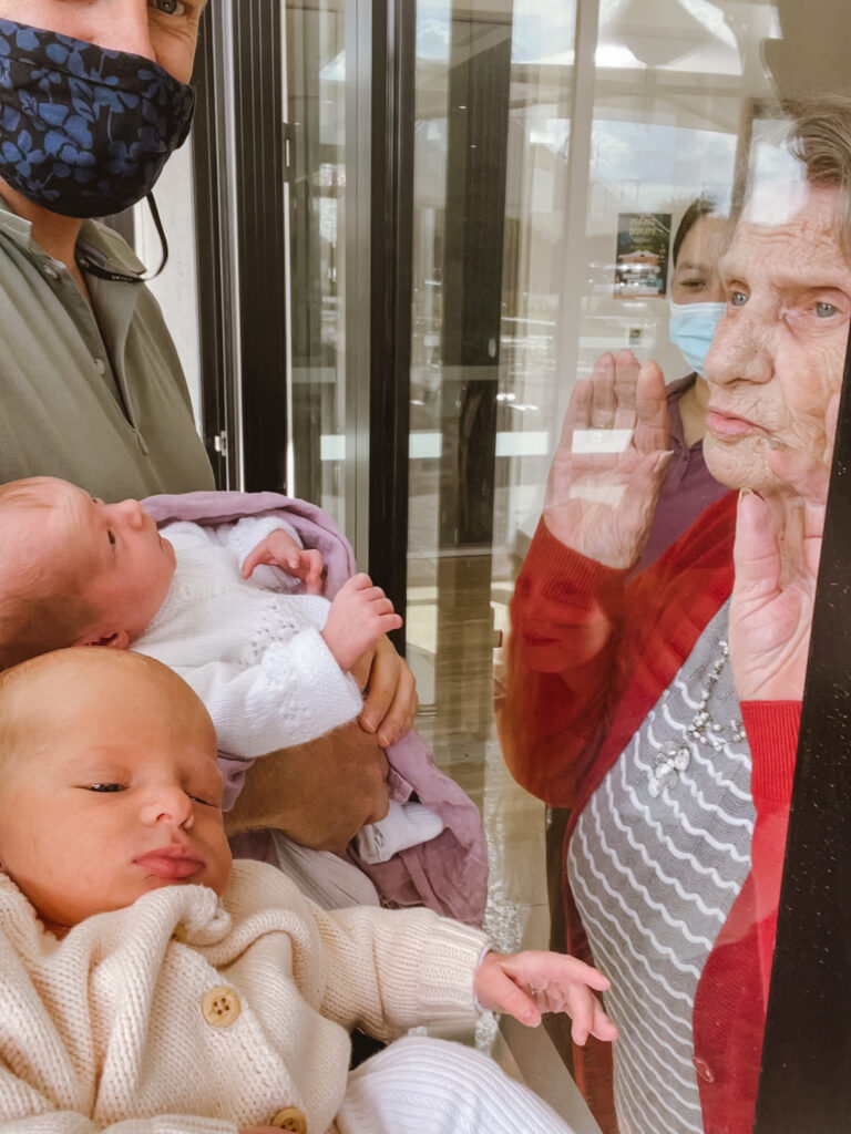 Elderly woman looking through glass at two new borns