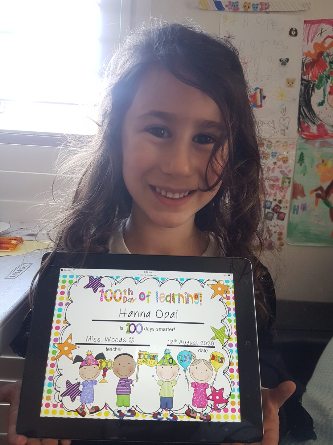 a young girl with dark brown hair and caucasian skin holding a certificate