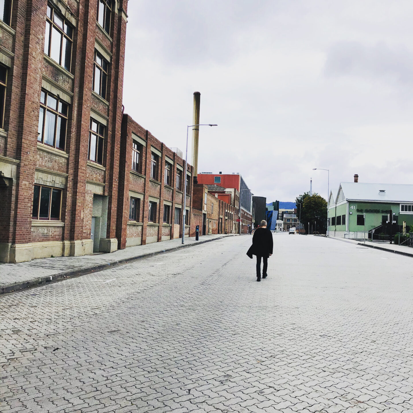a person in black walking down an empty street